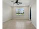 A minimalist bedroom with tile flooring, ceiling fan, and a bright window at 7505 Carissa, Punta Gorda, FL 33955