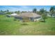 Rear view of home featuring a screened-in pool, lush green lawn, mature trees, and tropical plants at 7505 Carissa, Punta Gorda, FL 33955
