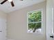 This bedroom features a ceiling fan, a window overlooking foliage, neutral paint, and a white door at 8849 Attalla Ave, North Port, FL 34287