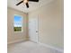This bedroom features a window overlooking green landscape, ceiling fan, neutral paint, and a white door at 8849 Attalla Ave, North Port, FL 34287