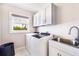 Well-lit laundry room featuring a modern washer and dryer, ample cabinet space, and a utility sink at 10233 St Paul Dr, Port Charlotte, FL 33981