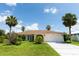 Single-story home with a two-car garage, tropical landscaping, a green lawn, and a sunny blue sky at 1612 Blue Lake Cir, Punta Gorda, FL 33983