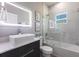 Modern bathroom featuring a stylish vanity, illuminated mirror, and bathtub with a glass enclosure and marble tile at 19160 Ruskin Ave, Port Charlotte, FL 33954