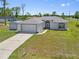 View of a light blue single-Gathering home with an attached 2-car garage, a shed, and a green front lawn at 1981 Arena Ln, North Port, FL 34286