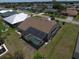 Back aerial view of a home with a screened-in pool area, and green landscaping at 23090 Ambassador Ave, Port Charlotte, FL 33954