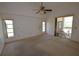 Spacious carpeted bedroom featuring a ceiling fan and sliding door access to outdoor pool area at 23090 Ambassador Ave, Port Charlotte, FL 33954