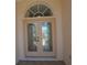 Elegant double front doors featuring decorative glass and an arched transom window, enhancing the home's curb appeal at 23090 Ambassador Ave, Port Charlotte, FL 33954
