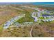 Drone view showcases a community with a central pool and tennis court, surrounded by natural beauty and homes at 25312 E Lenox Cir, Punta Gorda, FL 33950