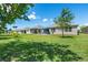 Back view of home featuring a large lawn, screened in patio and view of neighborhood homes at 25312 E Lenox Cir, Punta Gorda, FL 33950