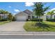Charming one-story home with a well-manicured lawn, a two-car garage, and lush landscaping under a partly cloudy sky at 25312 E Lenox Cir, Punta Gorda, FL 33950