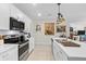 Modern kitchen features stainless steel appliances, white cabinetry, and an island sink with artistic hanging lights at 25312 E Lenox Cir, Punta Gorda, FL 33950