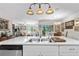 Bright kitchen island with stainless steel sink, dishwasher, breakfast bar, pendant lights and view to sunroom at 25312 E Lenox Cir, Punta Gorda, FL 33950
