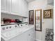 Bright laundry room with white appliances, cabinets, tiled floors and decorative artwork at 25312 E Lenox Cir, Punta Gorda, FL 33950