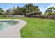 View of the lush green backyard featuring pool, an awning and wooden fence at 406 Merlin Ct, Brandon, FL 33510