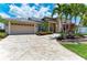 Charming front exterior featuring lush landscaping, decorative driveway, and a two-car garage at 414 Caicos Dr, Punta Gorda, FL 33950