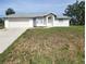 Charming single-story home featuring a clean white exterior, attached garage and a well-maintained lawn at 4390 Wischamper St, Port Charlotte, FL 33948
