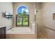 A bright bathroom with a soaking tub, glass shower and a large window with green views at 501 Fairmont Ter, Port Charlotte, FL 33954