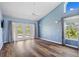 A blue bedroom with hardwood floors, a ceiling fan, and a French door leading to an outdoor patio at 501 Fairmont Ter, Port Charlotte, FL 33954