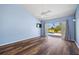 A blue bedroom with hardwood floors, ceiling fan, and sliding glass door leading to an outdoor patio at 501 Fairmont Ter, Port Charlotte, FL 33954