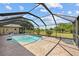 Screened-in pool is surrounded by a concrete patio and manicured lawn with mature tropical landscaping at 501 Fairmont Ter, Port Charlotte, FL 33954