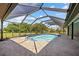 A screened-in pool basks under a blue sky within a black aluminum pool cage and concrete patio at 501 Fairmont Ter, Port Charlotte, FL 33954