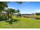 Beautiful waterfront backyard with lush grass, palm trees, and a private dock for enjoying the tranquil canal views at 69 Bunker Rd, Rotonda West, FL 33947