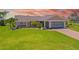 Charming single-story home with a well-manicured lawn, mature palms, and an attached two-car garage at 69 Bunker Rd, Rotonda West, FL 33947