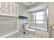Bathroom featuring a toilet next to a combination shower and tub plus upper cabinet with shelving at 6916 Rex Ln, Sarasota, FL 34243