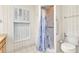 Bathroom showcasing a toilet and walk-in shower with a blue and white curtain, plus upper cabinet with shelving at 6916 Rex Ln, Sarasota, FL 34243