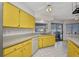 Eat-in kitchen offers yellow cabinets, white appliances, white tiled flooring, and a slider to the lanai and pool at 6916 Rex Ln, Sarasota, FL 34243