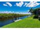 Waterfront backyard with green grass and a private dock surrounded by trees at 695 Macedonia Dr, Punta Gorda, FL 33950