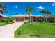 Charming one-story home boasts a lush green lawn, mature palm trees, and a paved driveway leading to a two-car garage at 695 Macedonia Dr, Punta Gorda, FL 33950