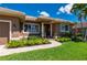 The front of this home features manicured shrubs, lush grass, columns, and a brick walkway that leads to the front door at 695 Macedonia Dr, Punta Gorda, FL 33950