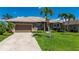 Charming single-story home with lush landscaping, a paved driveway, and a two-car garage at 695 Macedonia Dr, Punta Gorda, FL 33950
