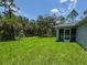 A spacious backyard features vibrant green grass, mature trees, and a screened-in lanai at 7381 De Brita Rd, North Port, FL 34291