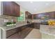 Well-equipped kitchen featuring dark wood cabinetry, granite countertops, tile backsplash, and stainless steel appliances at 7381 De Brita Rd, North Port, FL 34291