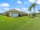 Lush green backyard with palm trees and a view of the screened-in pool area at 85 Long Meadow Ct, Rotonda West, FL 33947