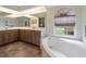 Bright bathroom featuring a large soaking tub, a big window, double sinks and ample counter space at 85 Long Meadow Ct, Rotonda West, FL 33947
