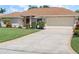 Single-story home with a two car garage, green lawn, beautiful landscaping and long driveway at 85 Long Meadow Ct, Rotonda West, FL 33947