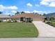 Charming single-story home with a green lawn, beautiful landscaping, and a long driveway at 85 Long Meadow Ct, Rotonda West, FL 33947