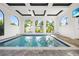Stylish indoor pool with arched windows, stone flooring, and bright, open space at 10161 Eagle Preserve Dr, Englewood, FL 34224