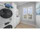 Bright laundry room with stacked washer and dryer, ample cabinet space, and a view of the outdoors at 10161 Eagle Preserve Dr, Englewood, FL 34224