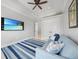 Comfortable sitting area featuring a blue sofa, ceiling fan, and mounted TV at 10161 Eagle Preserve Dr, Englewood, FL 34224