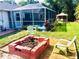 Landscaped backyard featuring a brick fire pit and screened-in pool with a dining gazebo at 1017 Guild St, Port Charlotte, FL 33952