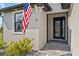Close-up of the front entry featuring a decorative glass door, American flag, and meticulously maintained landscaping at 111 Britt Rd, Rotonda West, FL 33947