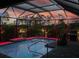 Serene outdoor pool and lanai at dusk, featuring custom lighting and a lush tropical backdrop at 111 Britt Rd, Rotonda West, FL 33947