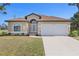 Inviting single-story home with a well-manicured lawn, arched windows, and a two-car garage at 118 Naomi Pl, Rotonda West, FL 33947