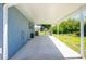 Exterior view showcasing a covered patio, with an air conditioning unit, adjacent to the yard at 12185 Weimar Ave, Port Charlotte, FL 33981