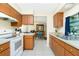 Bright kitchen featuring white appliances, wooden cabinets and a view into the adjacent dining area at 12185 Weimar Ave, Port Charlotte, FL 33981