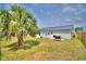 Grassy backyard with mature palm tree, patio, and gray siding at 13495 Newport Ave, Port Charlotte, FL 33981
